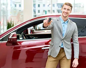Señor vestido formal al lado de un carro rojo, mostrando el control de alarma del auto